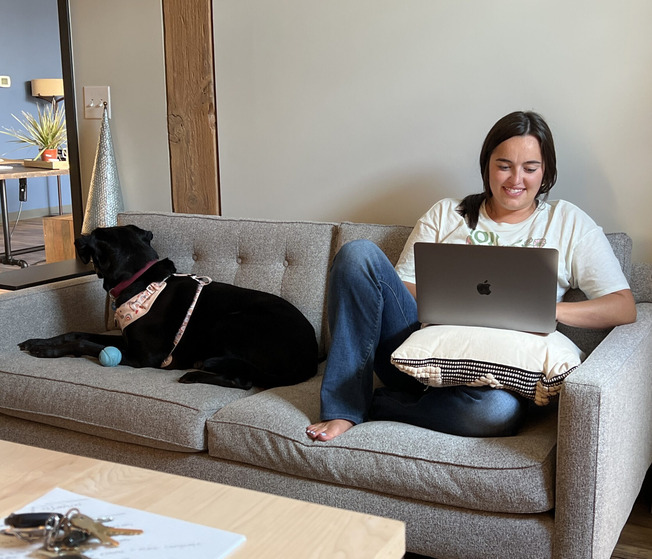 a girl working on the couch with her dog